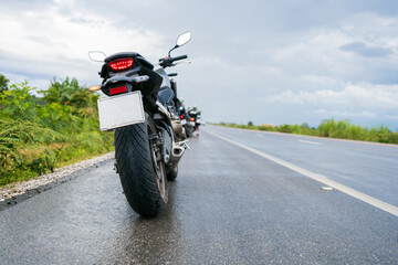 Obraz premium zbliżenie motocykl motoroweru jeździ przez kałużę na mokrej drodze w deszczu z nieostrością i nad światłem w tle