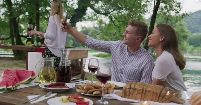 Couple having picnic french dinner party outdoor during summer holiday vacation near the river at beautiful nature
