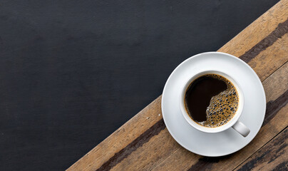 cup of coffee on black wooden floor background. space for text
