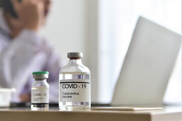 scientist working in laboratory with bottle of Covid-19 vaccine 