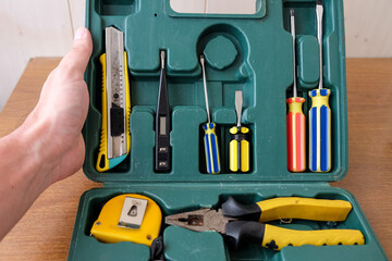 Man hand opens old square green tool box with manual set tools for home repair. Top view