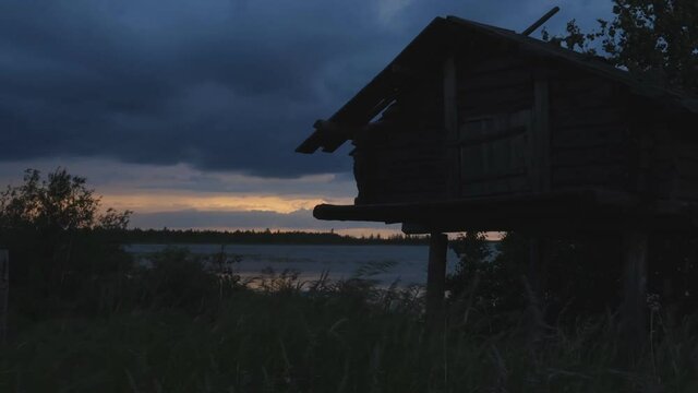 A house on stilts on the shore of the lake. Evening, twilight.