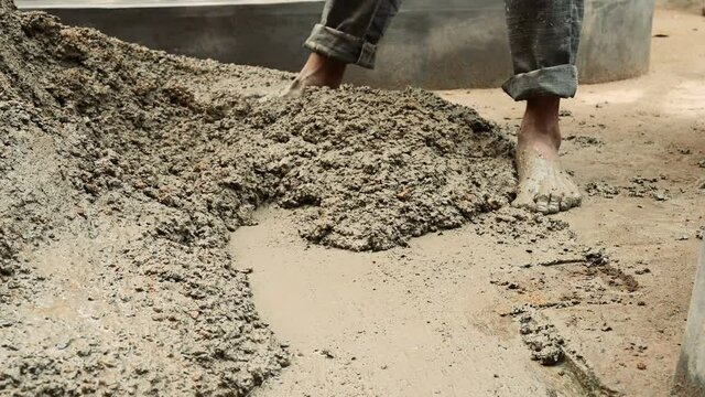 Indian labour mixing cement and water manually on floor using a shovel. Stock footage.