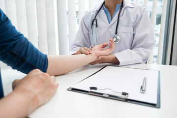 The doctor is measuring the heart rate by pressing the wrist of the patient in the hospital.