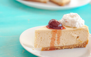 portion of cheesecake with jam on a white plate with cream