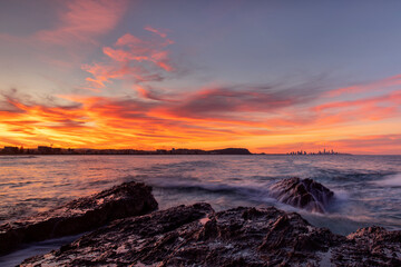Colourful sunset views and ocean tide over the rocks at Currumbin Rock Gold Coast