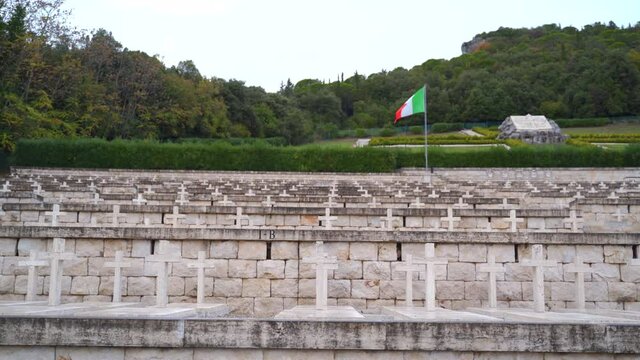 View of single red, white and green Italian flag above rows of white stone cross above several tombs at Polish cemetery, Monte Cassino, Italy, static
