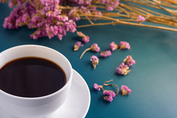 Close-up of a white coffee cup with purple flower blur background