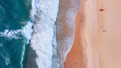 Fototapeta na wymiar Top down aerial view over ocean waves with surf livesaver boat and board on the beach