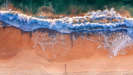 Top down view of a person walking along the beach and ocean surf © Bostock