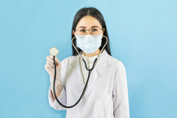 Smart young asian female doctor in lab coat with Medical face mask,white latex medical gloves and stethoscope against blue background,health care concept