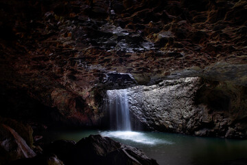 Fototapeta na wymiar Water flowing down the Natural Bridge in Springbrook, view under the cave. Gold Coast hinterland