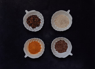 Obraz na płótnie Canvas Spices and grains in white cups on a black background. Top view