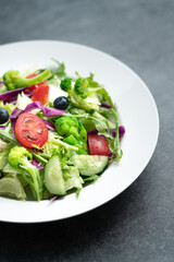 A plate of delicious and healthy green vegetable salad. A plate of delicious and healthy vegetable salad on a gray concrete floor.
