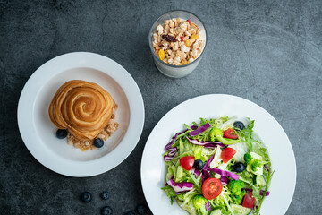 A plate of healthy and delicious salad and a bread.A plate of salad and a glass of oat milk on a gray concrete floor。