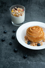 A breakfast bread and a glass of breakfast oat milk. A breakfast bread and a cup of breakfast oatmeal yogurt.