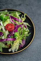 Close-up of a plate of delicious healthy green vegetable salad. A plate of delicious and healthy vegetable salad on a gray concrete floor.
