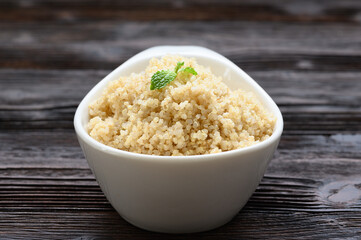 Bowl of boiled quinoa on wood background