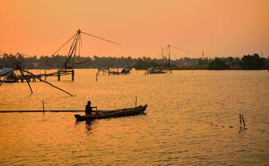 A fishing boat sailing in Kochi backwaters during sunset.