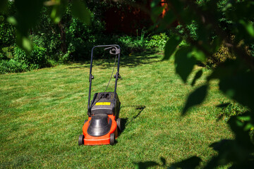 The lawnmower stands on the green grass.