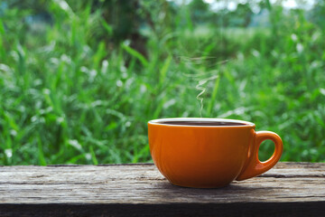 Close up of Black hot drink coffee cup on an old wooden table with a green nature landscape