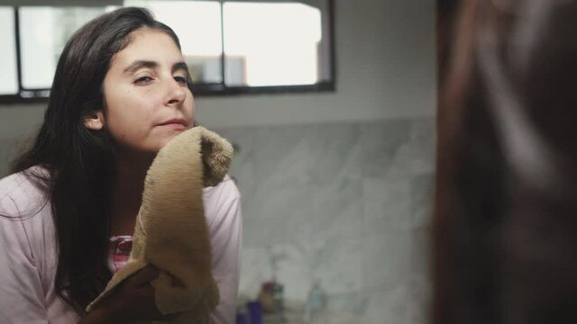 Close up girl wipes her face with a towel looking at the mirror. morning female routine, facial skin care.