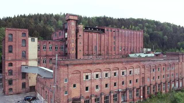 Lost place factory in east Germany from socialist times Drone heading out backwards while keeping building in view on an overcast day