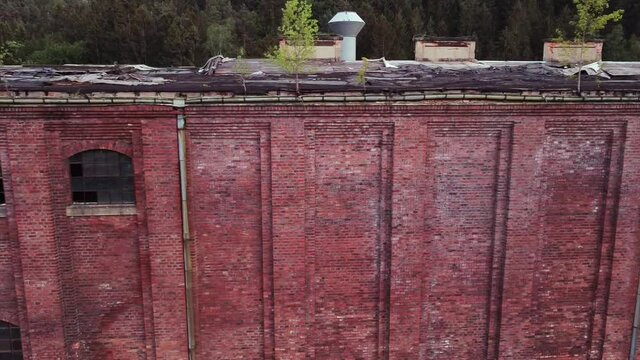 Drone flies horizontally to the left outside of a lost place socialist VEB Factory in eastern Germany at sundown