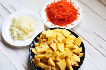 raw carrots grated, chopped onions, potatoes. Preparing to cook baked potatoes with vegetables.