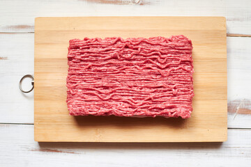 Raw minced meat on a wooden background.