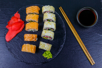 Set of sushi rolls on a black stone slate. Top view