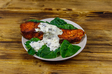 Grilled salmon fillet with spinach and tartare sauce on wooden table