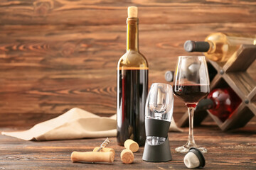 Aerator with bottle and glass of wine on wooden background