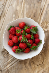Topview image of strawberries in a white rustic bowl
