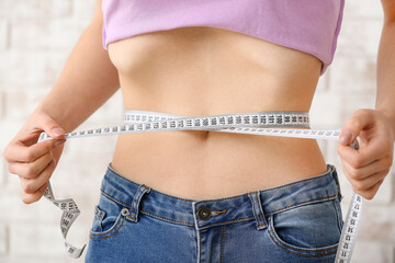 Woman measuring her waist, closeup. Concept of anorexia