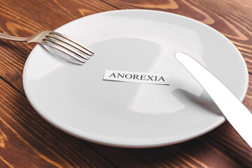 Plate and cutlery with word ANOREXIA on table