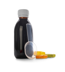 Bottle of cough syrup with candies on white background