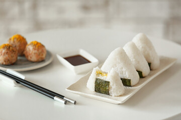 Plate with traditional Japanese onigiri and sauce on table