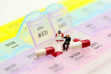 Miniature people : Doctor showing patient medication with Pill Box & Daily Medicine