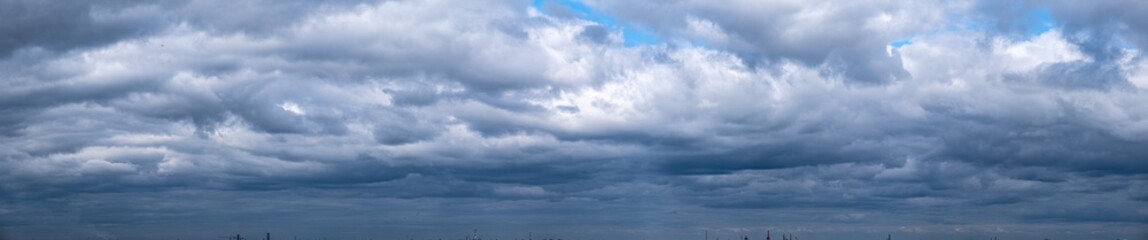 Panorama of dramatic rainy cloudy blue sky. Cumulus clouds are white and gray outdoors.