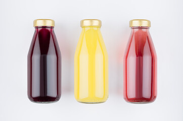Collection of fresh fruits juices - yellow, pink, violet in glass bottles on white background, mock up for design, advertising, branding product.