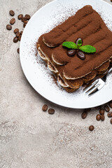 Classic tiramisu dessert on ceramic plate on concrete background