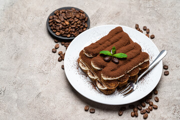 Classic tiramisu dessert on ceramic plate on concrete background