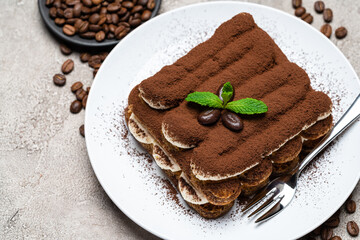 Classic tiramisu dessert on ceramic plate on concrete background
