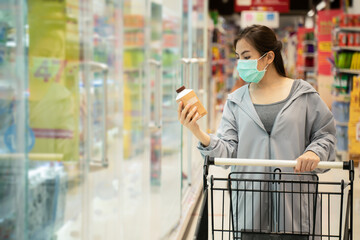 New normal after covid epidemic and shopping concept,young asian woman new lifestyle shopping at supermarket with face shild or mask protection hand choose consumer products as new normal lifestyle