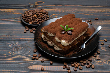 Classic tiramisu dessert on ceramic plate on wooden background