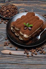 Classic tiramisu dessert on ceramic plate on wooden background
