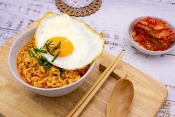 Spicy ramen (noddle) on a wooden board with side dish (Kimchi).