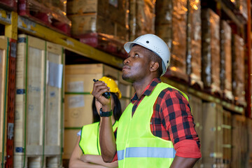 Warehouse worker using handheld radio receiver for communication in a large warehouse. © visoot