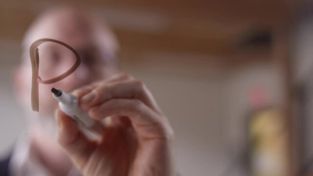 "Purpose-Led" written on clear plexiglass with a dry erase marker by a modern businessman